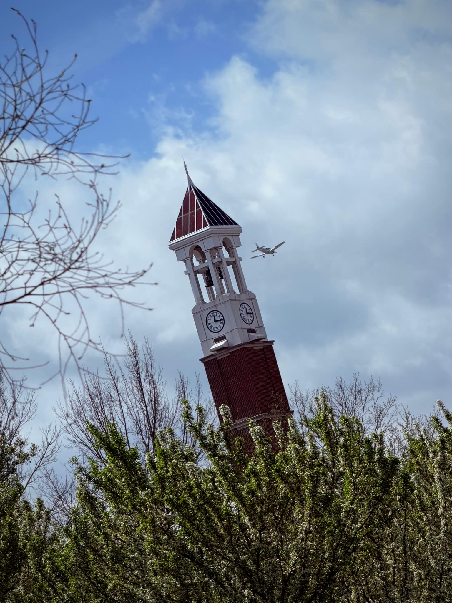 The Purdue University bell tower as an airplane flies overhead.